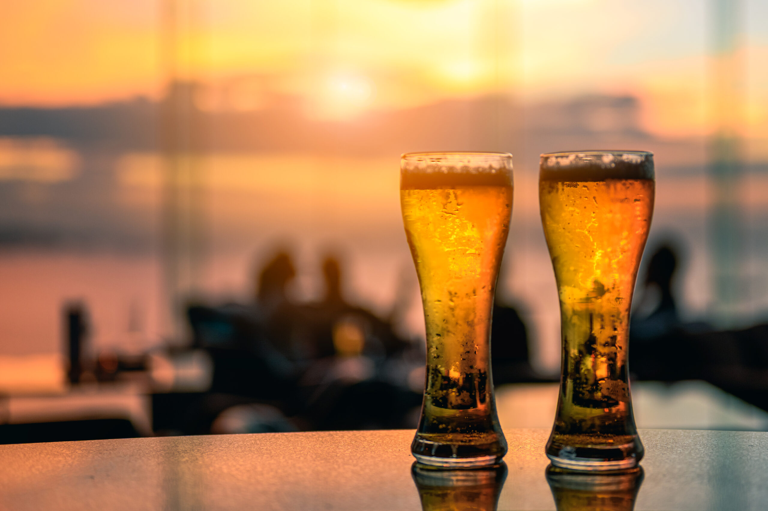 Glass of beer on a pub at sunset background.