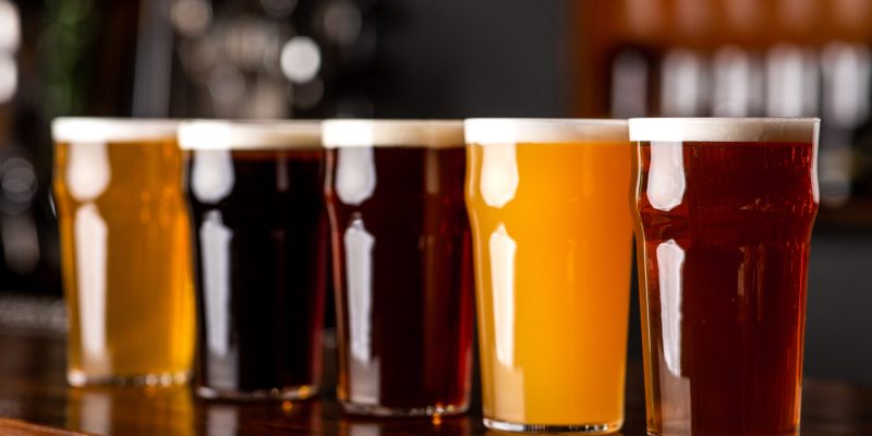 Beer assortment. Dark, light, unfiltered, lager and ale in glasses on wooden bar counter, close up, free space