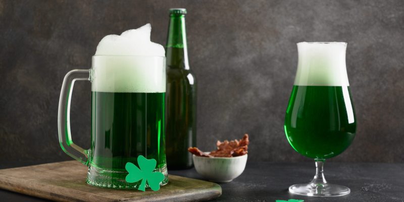 Patrick's day green beer in pint , snack and jerky meat on dark background. Shamrock symbol of luck.