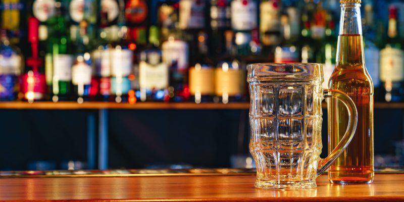 Beer glass and bottle on wooden countertop in a pub