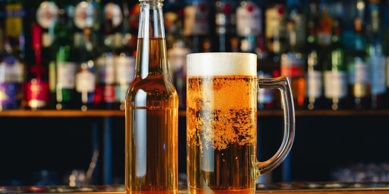 Beer glass and bottle on wooden countertop in a pub