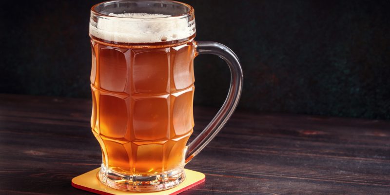 Lager beer mug on wooden table with copy space in dark ambience